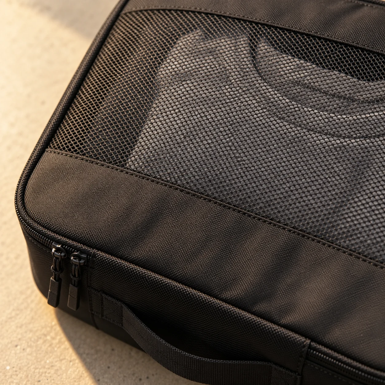 Fine mesh panel and solid polyester border on the large black packing cube